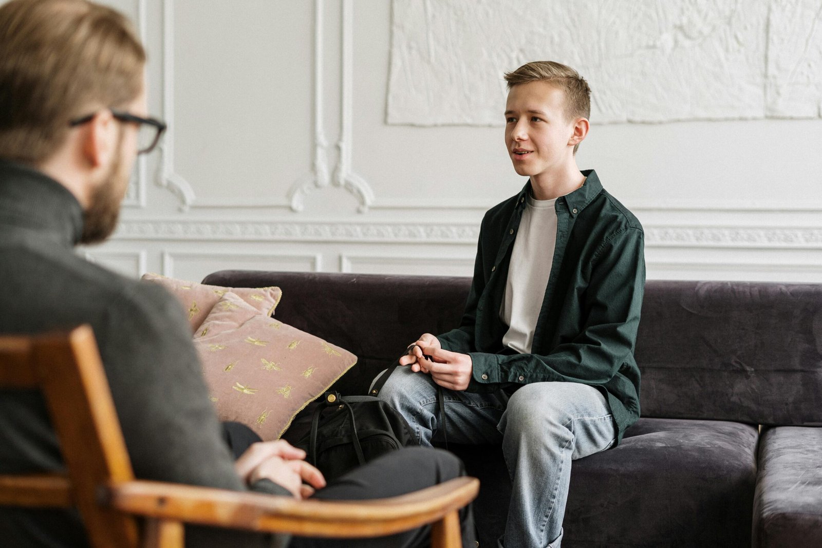 pexels-photo-4100661-4100661 A teenage boy in a counseling session discussing with a therapist in an office setting.