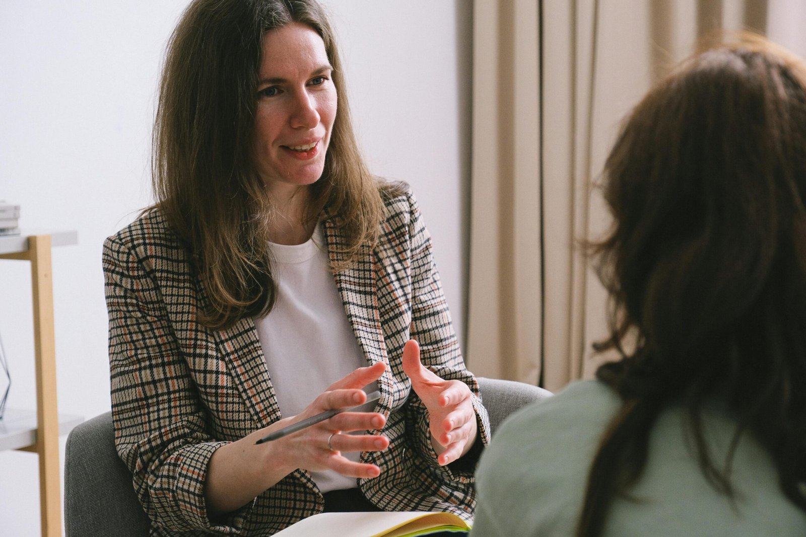 pexels-photo-7176288-7176288 Pensive woman psychologist with brown hair in stylish clothes sitting and talking with unrecognizable female in light room